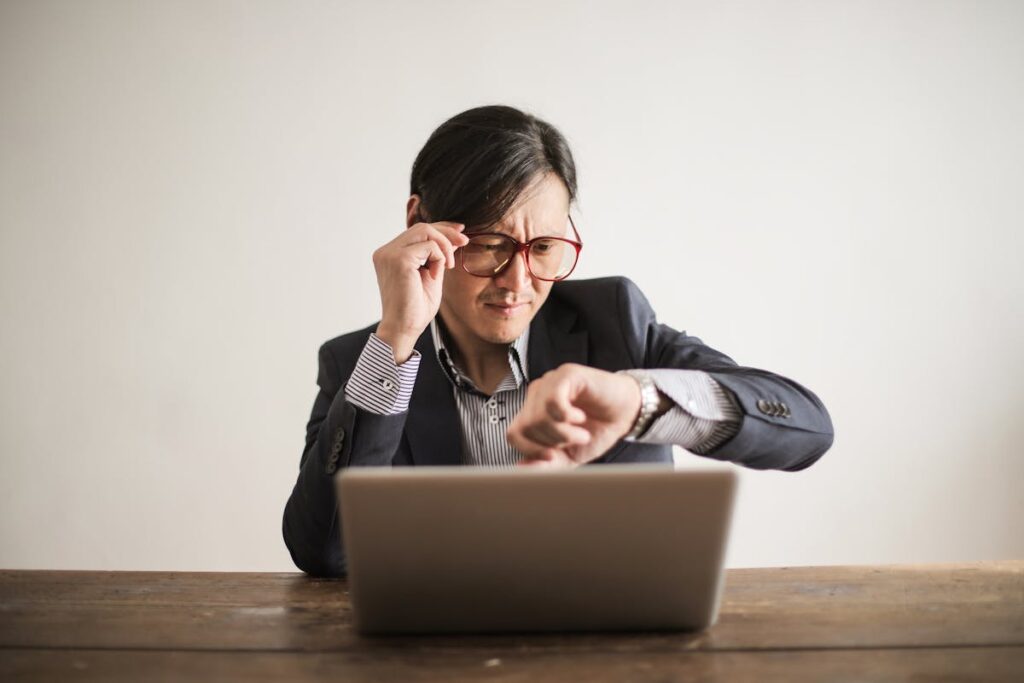 Confused businessman checking time on wristwatch